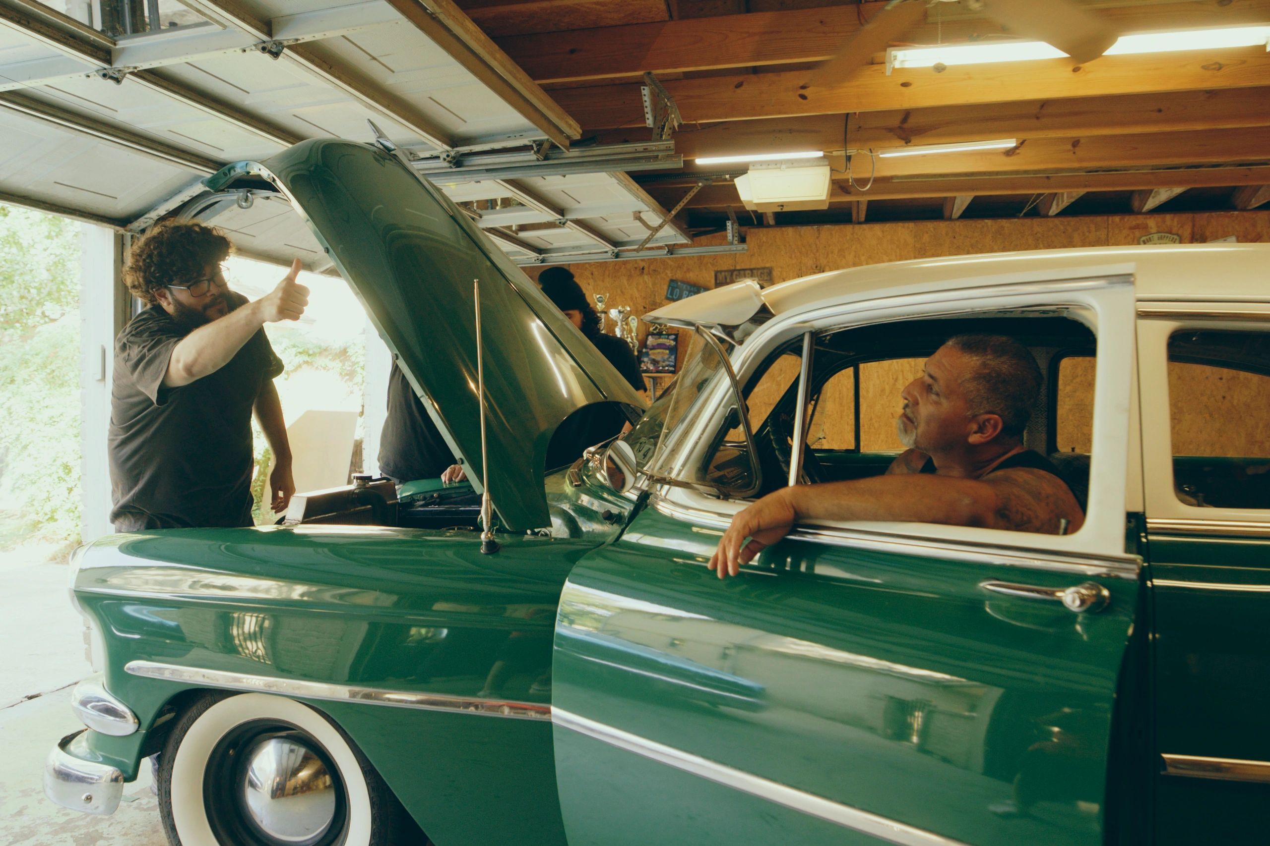 Family working on a vintage car in a garage